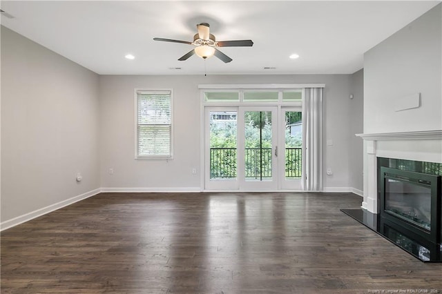 unfurnished living room featuring ceiling fan, a tiled fireplace, baseboards, dark wood finished floors, and recessed lighting