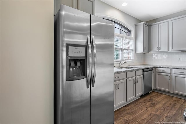 kitchen with stainless steel appliances, gray cabinets, dark wood-type flooring, backsplash, and a sink