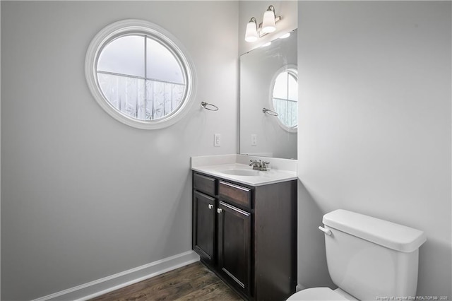 bathroom with wood finished floors, toilet, vanity, and baseboards
