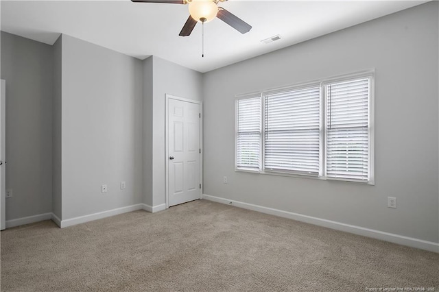 spare room with a ceiling fan, light colored carpet, and baseboards