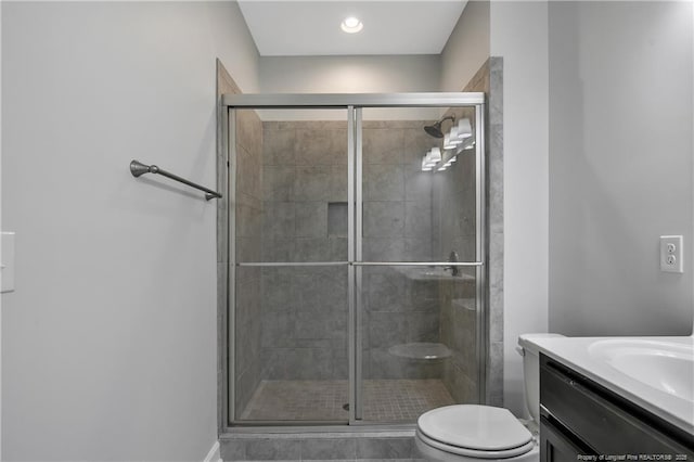 bathroom featuring a shower stall, toilet, vanity, and baseboards
