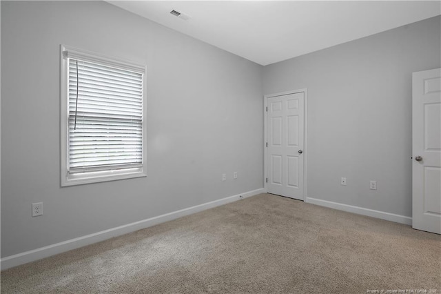 empty room featuring light colored carpet and baseboards