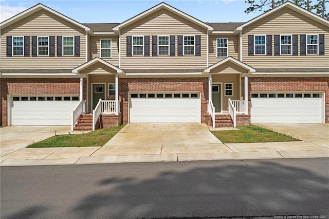view of property featuring a garage, brick siding, and driveway