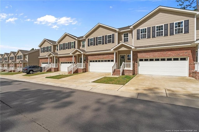multi unit property with brick siding, a garage, a residential view, and driveway