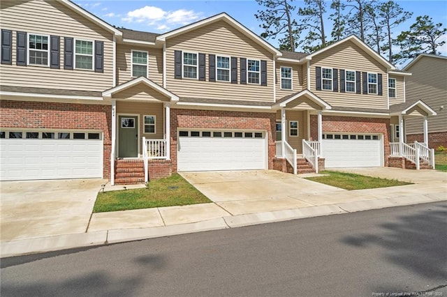 view of property with brick siding, a garage, and driveway