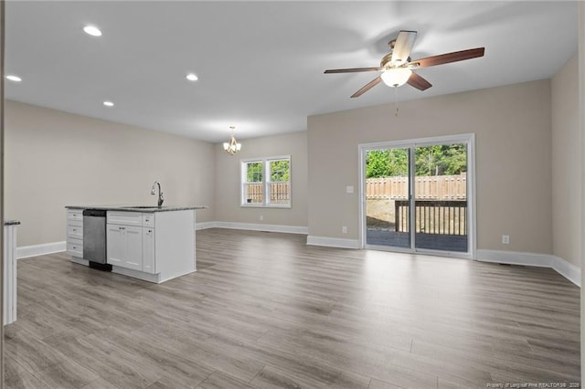 unfurnished living room featuring a chandelier, baseboards, a ceiling fan, wood finished floors, and recessed lighting