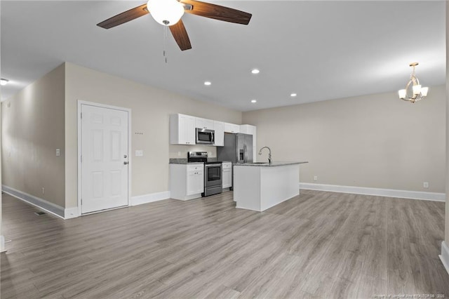 kitchen featuring stainless steel appliances, open floor plan, a sink, a ceiling fan, and baseboards