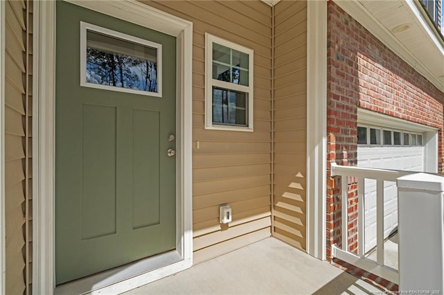 doorway to property featuring brick siding and a porch