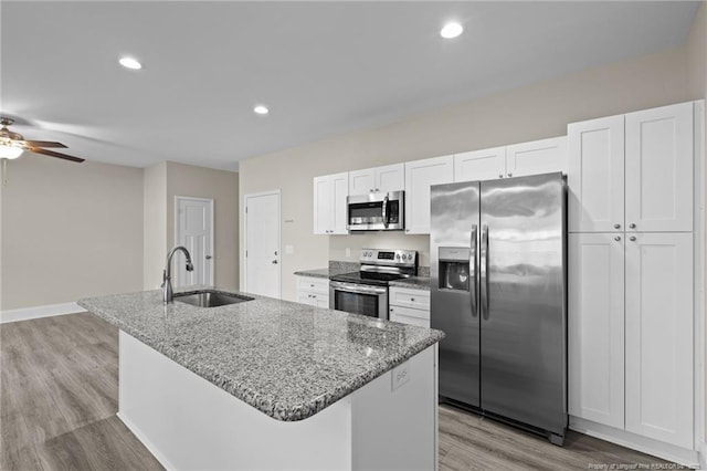 kitchen with appliances with stainless steel finishes, a sink, a kitchen island with sink, white cabinetry, and a ceiling fan