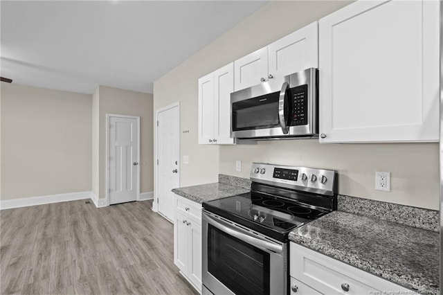 kitchen featuring stainless steel appliances, white cabinets, light wood-type flooring, and dark stone counters