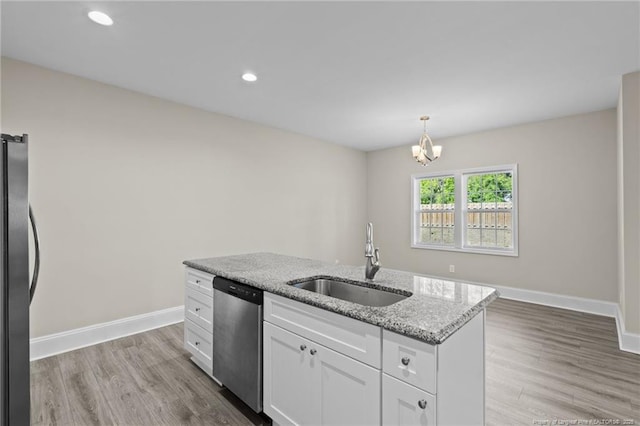 kitchen featuring a sink, dishwasher, freestanding refrigerator, white cabinetry, and light stone countertops
