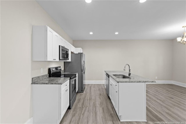 kitchen with stainless steel appliances, a sink, baseboards, dark stone countertops, and white cabinetry
