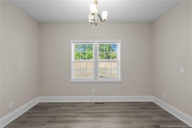 unfurnished room with a chandelier, baseboards, and dark wood-style flooring