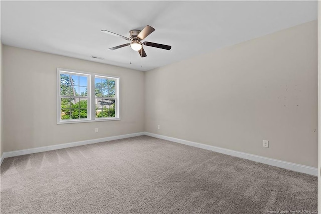 carpeted spare room with a ceiling fan and baseboards