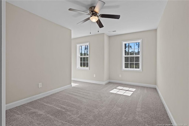 empty room with carpet floors, plenty of natural light, ceiling fan, and baseboards