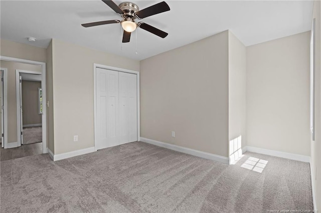 unfurnished bedroom with carpet, a closet, baseboards, and a ceiling fan