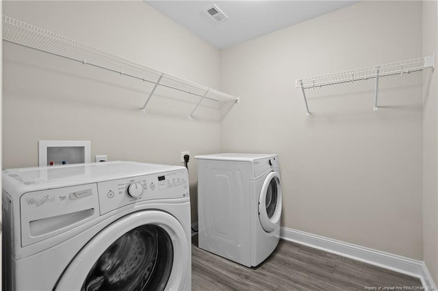 laundry room featuring washer and dryer, wood finished floors, and baseboards