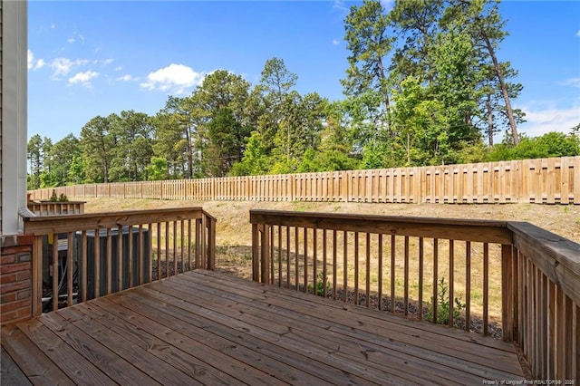 wooden terrace with a fenced backyard and view of wooded area