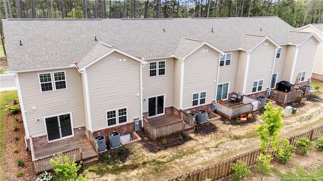 rear view of house featuring a wooden deck, central AC, fence, and a shingled roof