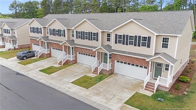 view of front of property with an attached garage, brick siding, and roof with shingles