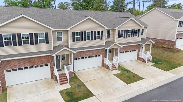 view of front of home featuring brick siding, a garage, and a shingled roof