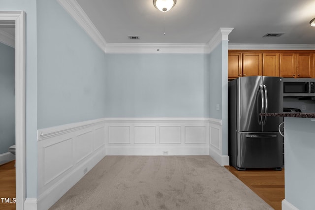 735 Portstewart Dr, Cary, NC 27519 - kitchen with stainless steel appliances, ornamental molding, wainscoting, brown cabinets, and dark stone countertops