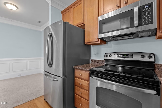 735 Portstewart Dr, Cary, NC 27519 - kitchen with appliances with stainless steel finishes, ornamental molding, dark stone counters, light wood-style floors, and brown cabinetry