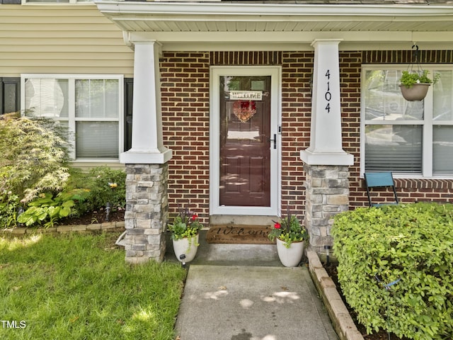 doorway to property featuring brick siding and covered porch