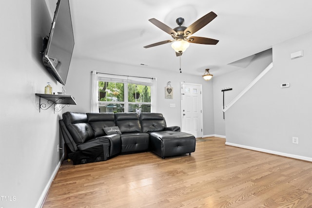 living room with a ceiling fan, light wood-style floors, and baseboards