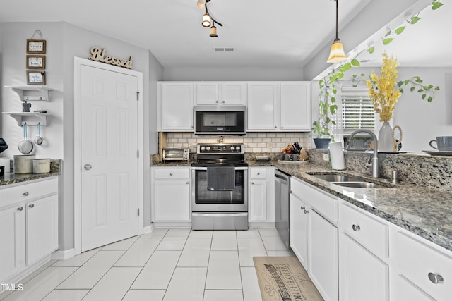 kitchen with appliances with stainless steel finishes, a sink, white cabinetry, stone countertops, and decorative backsplash