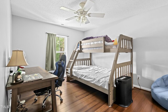 bedroom featuring wood finished floors, a textured ceiling, an office area, baseboards, and ceiling fan