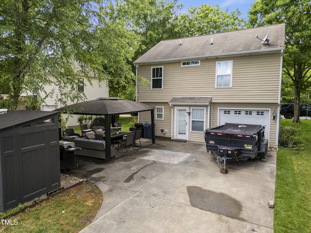back of property featuring a garage, an outdoor hangout area, a patio, concrete driveway, and a storage unit