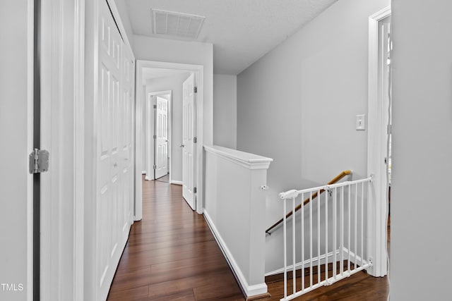 hall featuring an upstairs landing, dark wood-style flooring, and baseboards