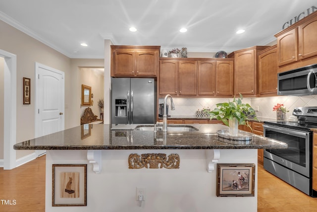 79 Heatherwood Dr, Chapel Hill, NC 27516 - kitchen featuring appliances with stainless steel finishes, a sink, crown molding, dark stone counters, and a kitchen island with sink