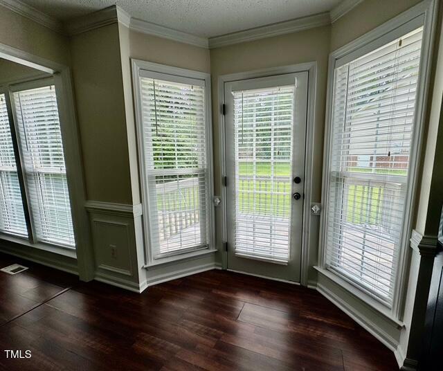 doorway featuring dark wood-style flooring, healthy amount of natural light, and crown molding