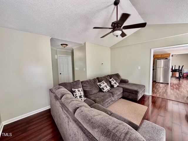 living room featuring wood finished floors, a ceiling fan, a textured ceiling, baseboards, and lofted ceiling