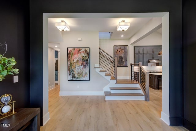 entryway with stairs, light wood-type flooring, and baseboards