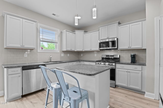 55 Prospectus Ln, Franklinton, NC 27525 - kitchen featuring stainless steel appliances, a sink, light wood-style floors, a center island, and tasteful backsplash