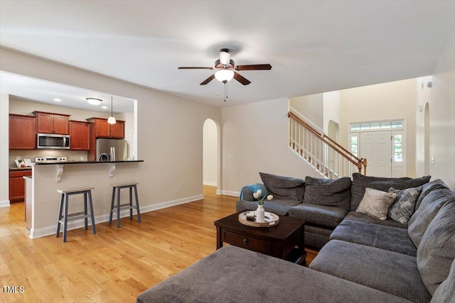68 Tanners Way, Clayton, NC 27527 - living area with arched walkways, stairs, light wood-type flooring, ceiling fan, and baseboards