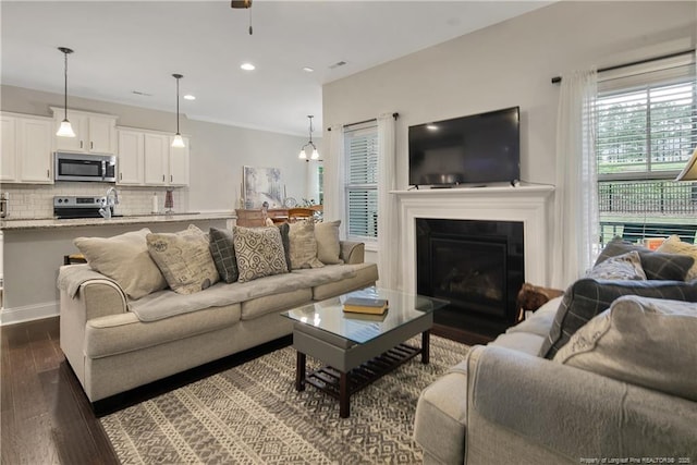 living room featuring dark wood finished floors, recessed lighting, and a glass covered fireplace