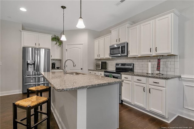 kitchen featuring stainless steel appliances, a sink, white cabinets, decorative backsplash, and dark wood-style flooring