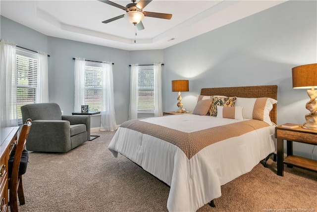 carpeted bedroom with a tray ceiling and a ceiling fan