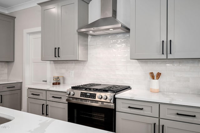703 E Markham Ave, Durham, NC 27701 - kitchen featuring wall chimney exhaust hood, stainless steel gas stove, gray cabinetry, decorative backsplash, and ornamental molding