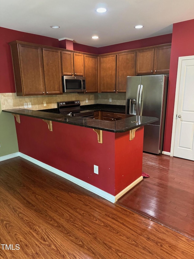 1671 Holly Grove Way, Durham, NC 27713 - kitchen with appliances with stainless steel finishes, a kitchen bar, a peninsula, dark wood-style floors, and recessed lighting