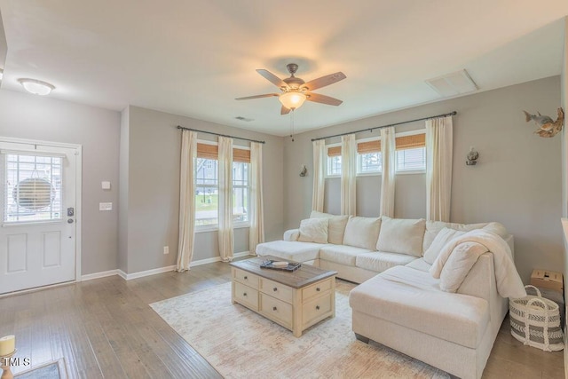 living area with plenty of natural light, a ceiling fan, light wood-type flooring, and baseboards