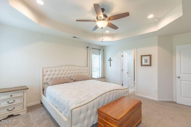 bedroom featuring a raised ceiling, light colored carpet, baseboards, recessed lighting, and ceiling fan