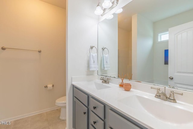 bathroom featuring toilet, tile patterned flooring, double vanity, and baseboards