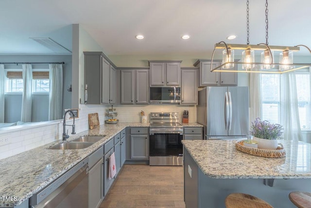 kitchen featuring appliances with stainless steel finishes, a sink, gray cabinets, recessed lighting, and tasteful backsplash