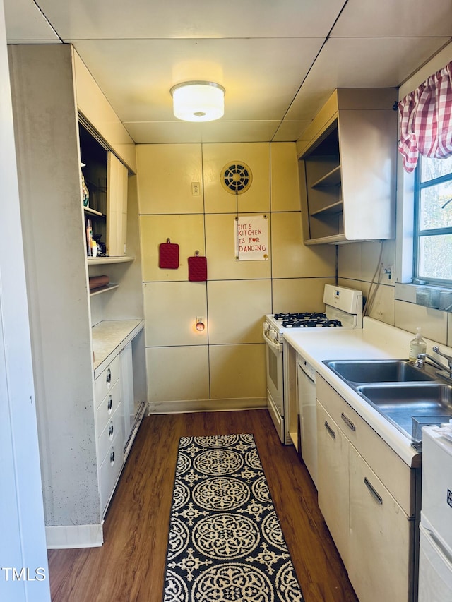 kitchen with open shelves, white appliances, a sink, light countertops, and dark wood-style flooring