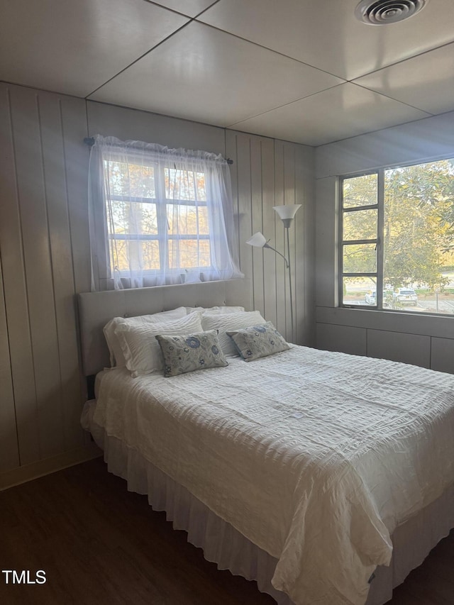 bedroom featuring wood finished floors, multiple windows, and wooden walls